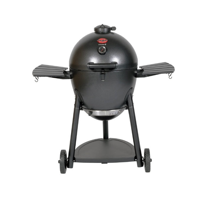 The Char-Griller AKORN Kamado Charcoal Grill includes cast iron cooking grates, a removable warming rack, steel side shelves, and a grill grate lifter, providing convenience and long-lasting performance.