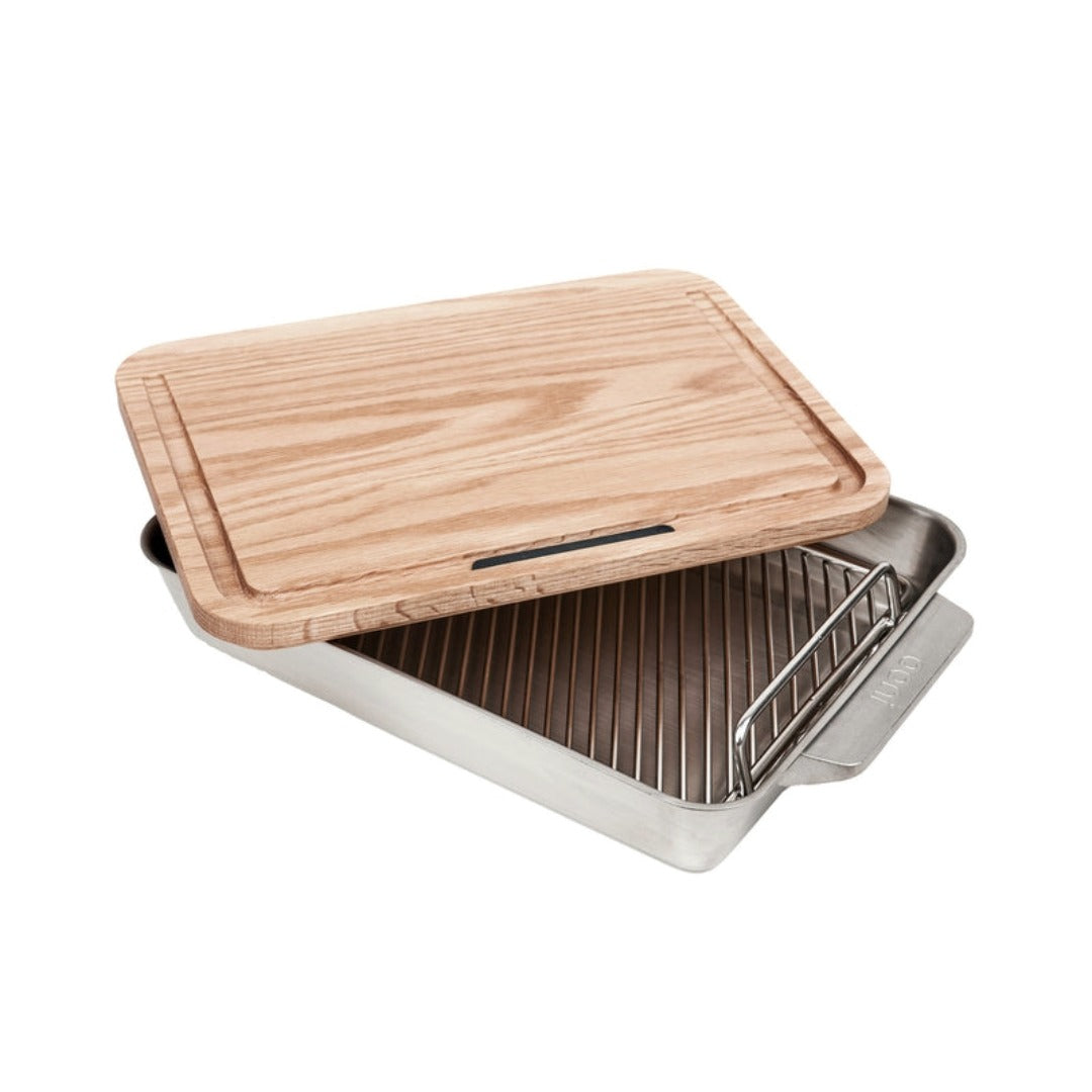 Ooni Roasting Pan paired with a premium white oak cutting board designed to capture juices for rich sauces and gravies.